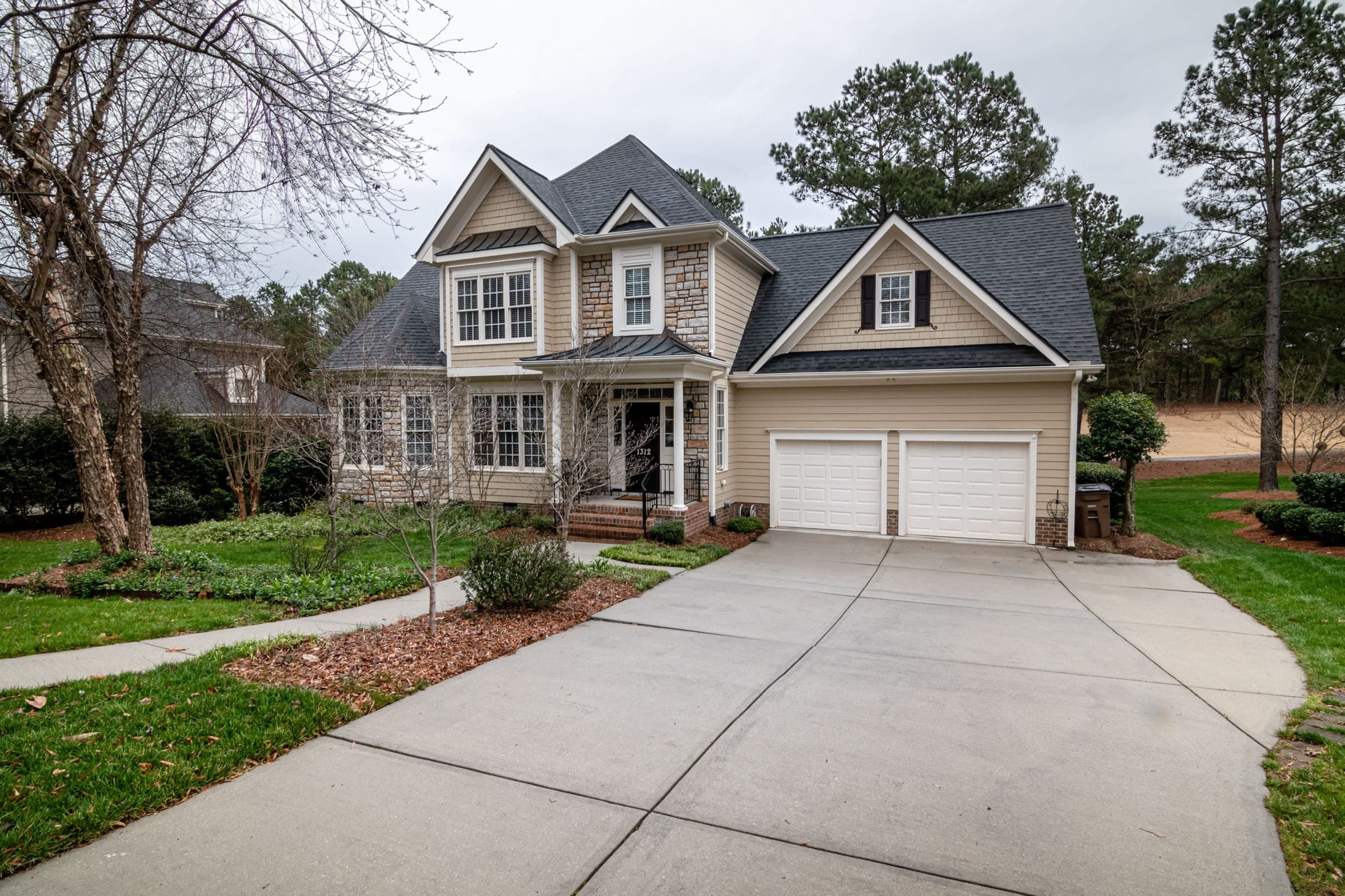 A two-storey house with a wide concrete driveway sweeping up to a two-car garage.