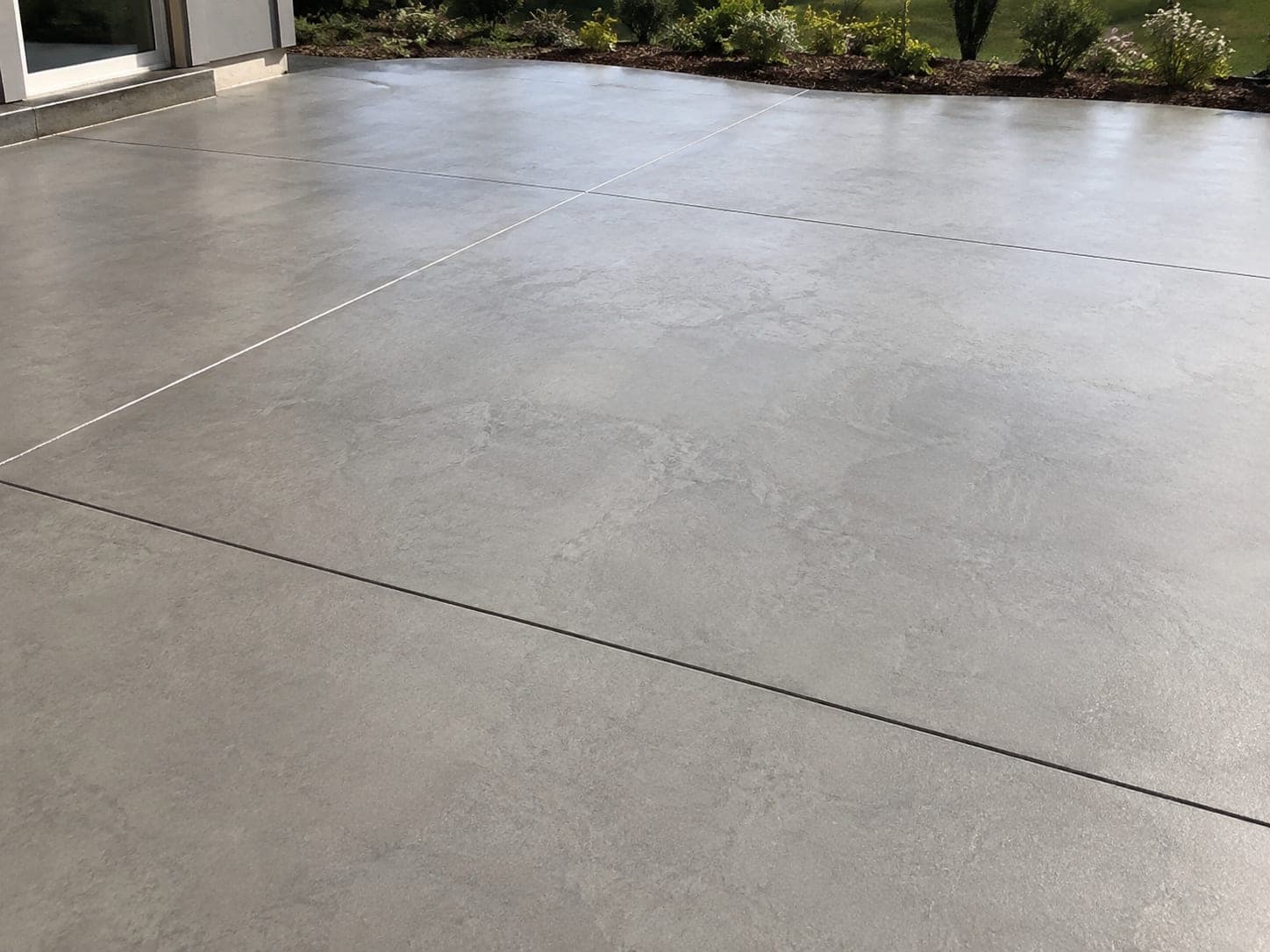A finished patio alongside a house, edged with planting.